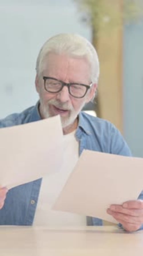 Old Man Celebrating Win while Reading Documents in Office, vertical video
