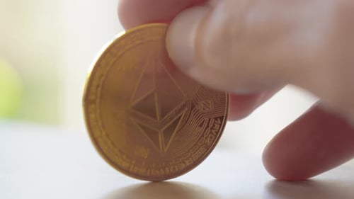 Spinning around golden Bitcoin BTC with fingers on a table, close up.