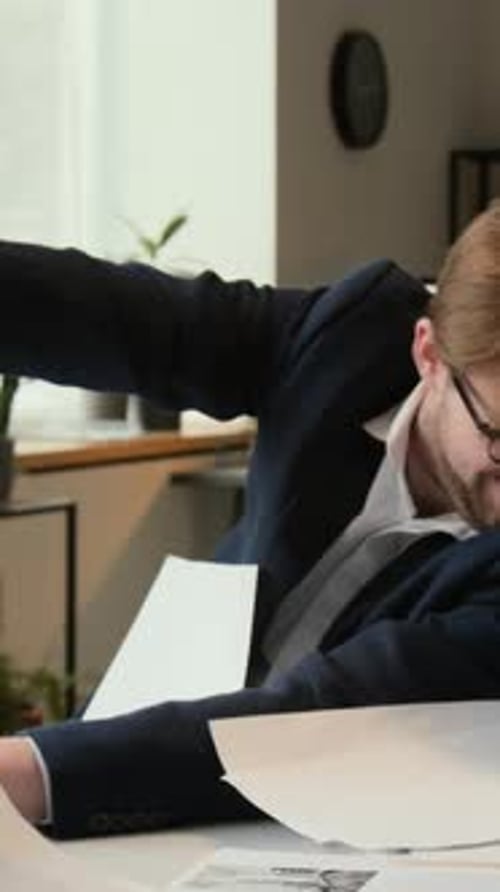 Vertikale eines vielbeschäftigten männlichen Managers, der Dokumente wegwinkt, die ihm während des Arbeitstages entgegenfliegen