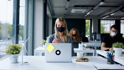 Young People with Face Masks Back at Work in Office After Lockdown