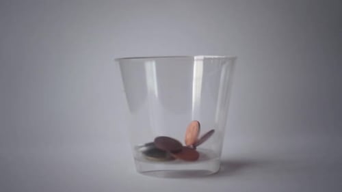 Slow Motion Of Coins Falling Into Jar With Clean White Background