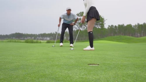 Close up of couple golfer swing clubs together on a scenic golf course.