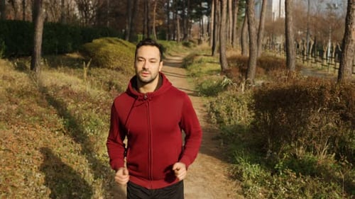 Man Running on Trail in Autumn Park - front view