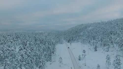 Drone shot chasing an EV driving in beautiful big snowy landscape in Norway.