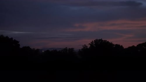 Fogos de artifício amarelos cintilantes explodem à distância com vermelho, nebuloso, roxo, brilho, câmera lenta