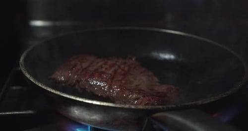 Beautiful close-up shot of a beef tenderloin cooked on a pan with oil inside an industrial kitchen.