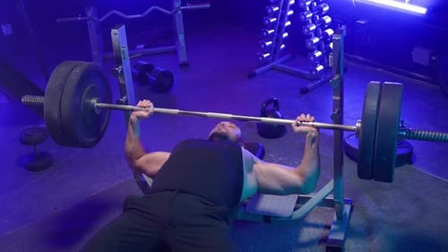 Bodybuilder, der auf einer Sportbank liegt und schwere Langhantel mit Gewichten schiebt