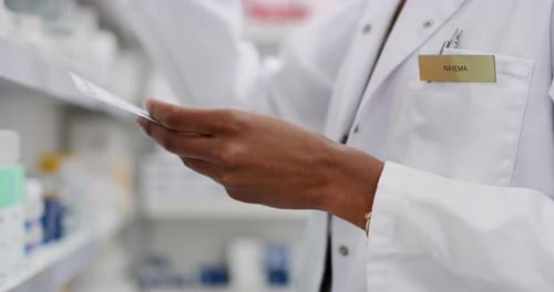 Pharmacist Selecting Medication From Shelf At Work