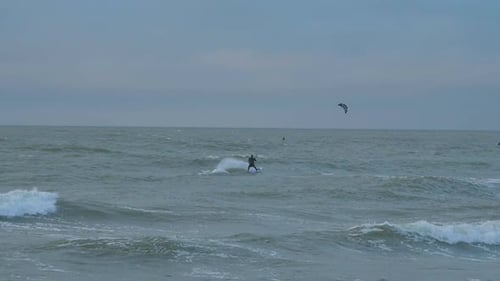 A group of people engaged in kitesurfing, overcast winter day, high waves, Baltic Sea Karosta beach