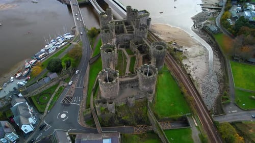 Drone flying over towers and ramparts of Conwy Castle, North Wales in UK. Aerial top-down forward