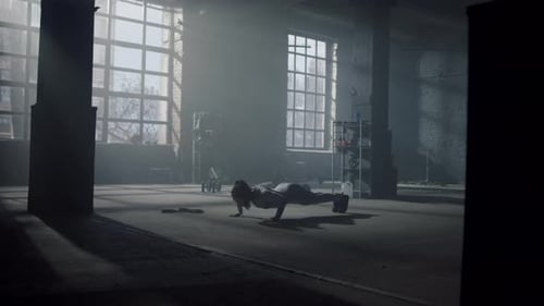 Woman Doing Pushups in Industrial Gym with Sunlight