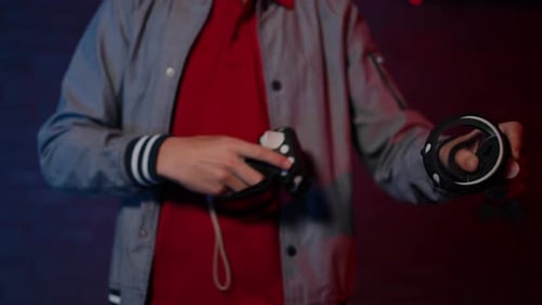 Young Player Holding VR Game Controllers in Dark Room