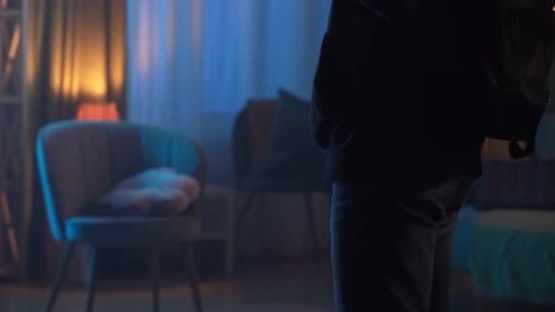 Shadowy Figure with Crowbar in Dim Room