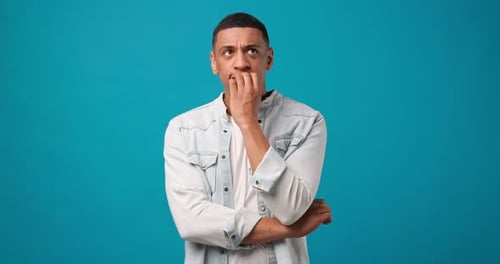 Worried Man Biting Nails on Teal Background