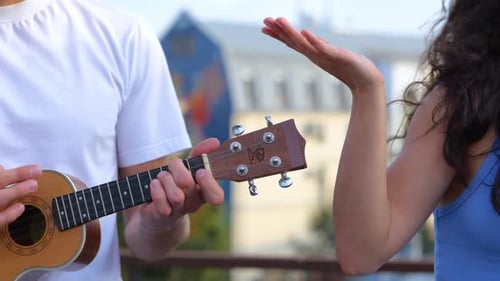 Close Up of Young Handsome Man Playing Ukulele Small Guitar While Beautiful Woman Singing in