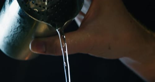 Close up of a professional bartender is preparing an elite alcoholic cocktail to customers at the