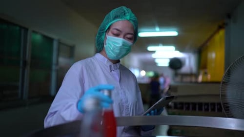 Ouvrier d'usine examinant une bouteille dans une usine, concept commercial de l'industrie technologique.