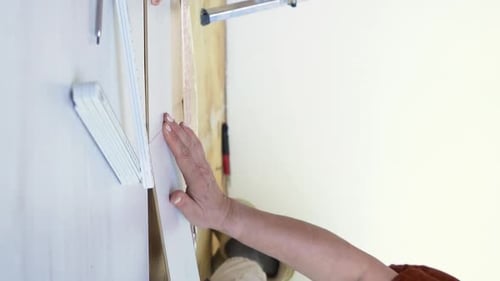 Adult Installing Wood Trim with Measuring Stick