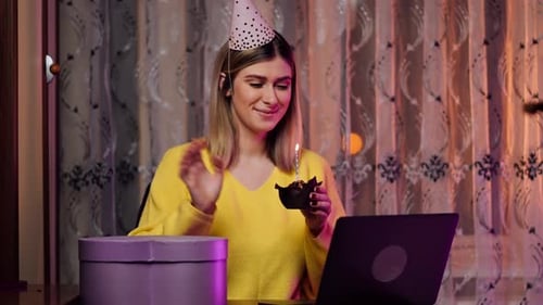 Woman Celebrates Birthday Online Holding Cupcake and Candle