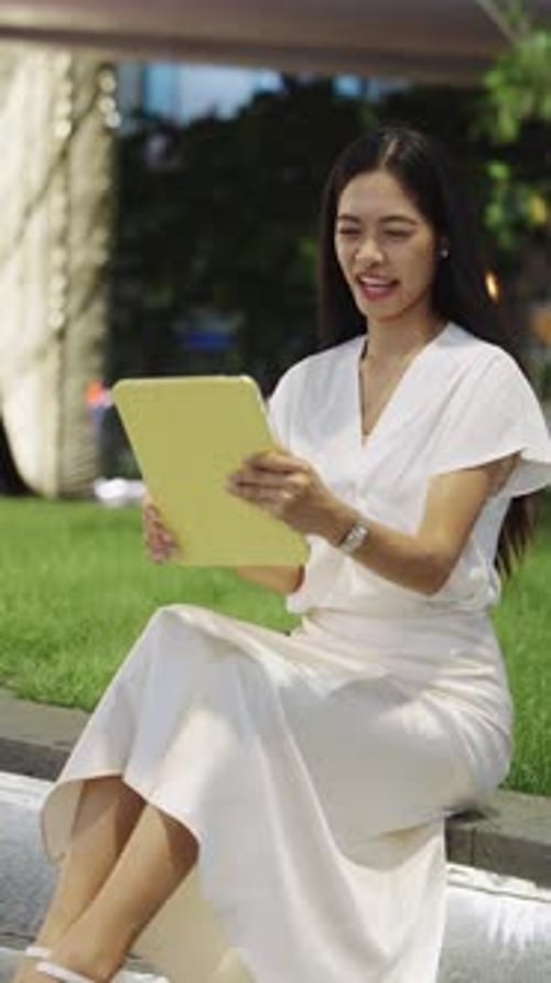 Businesswoman Sitting Outdoors Using Tablet