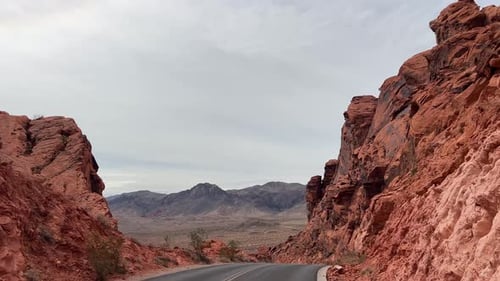 A Picturesque Road Beautifully Winding Through Stunning Red Rock Canyons Peacefully Under a Cloudy