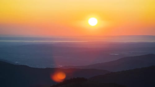 Zeitraffer eines farbenfrohen Sonnenuntergangs in wilden Bergen, dunkler Pinienwald, beleuchtet von hell untergehender Sonne