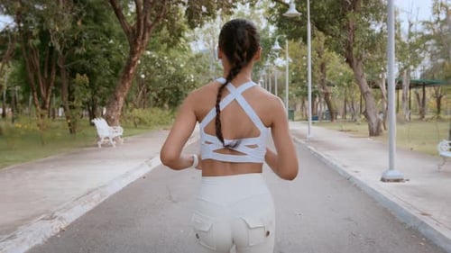 Young fitness woman in sportswear jogging in city park