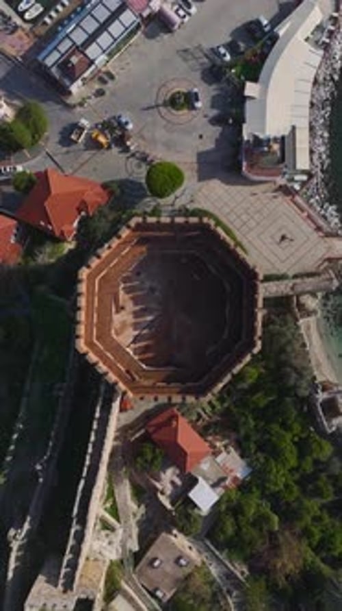 Vídeo vertical de la Torre Roja de Alanya capturado desde arriba con las murallas de la ciudad vieja hacia abajo