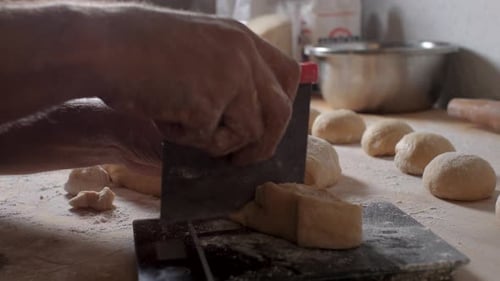 Young Latino worker in a Mexican bakery measuring, cutting, weighing on scales and forming loaves of