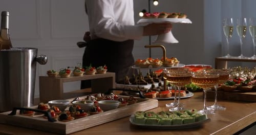 Waiter arranging appetizers for buffet at table, closeup