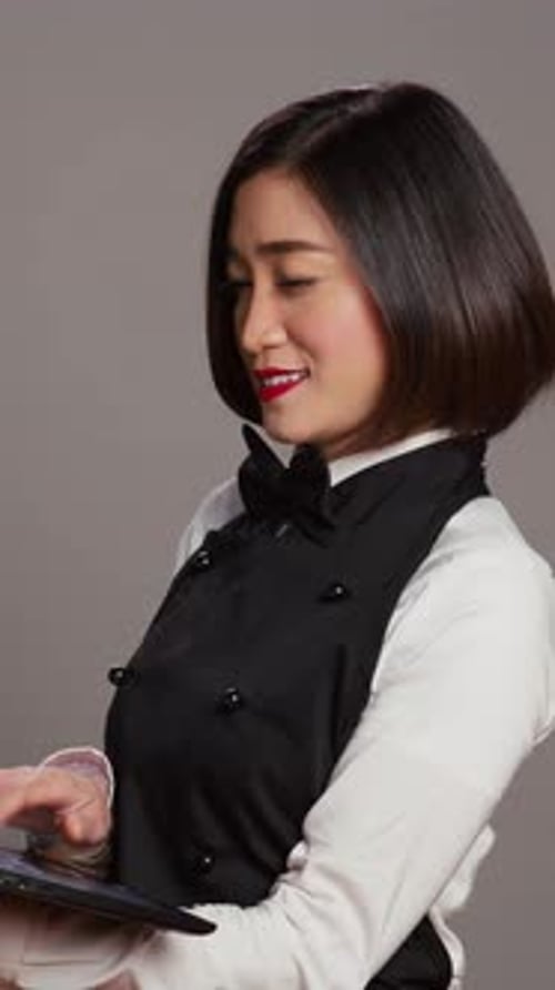 Vertical Video Asian Waitress Checking All Table Reservations Online on Laptop