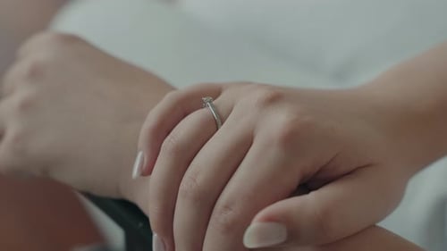 Elegant woman's hand displaying diamond engagement ring indoors