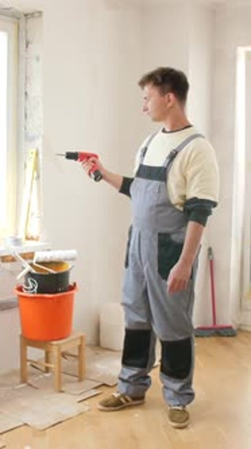 Man Holds Drill During Room Renovation