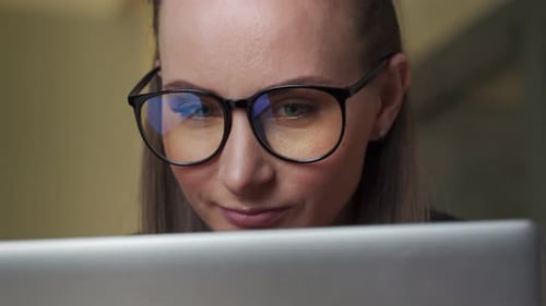 Portrait of a Young Business Woman with Glasses Working with a Computer in the Office Closeup