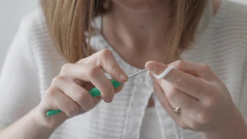 Woman Crocheting White Yarn with Crochet Hook