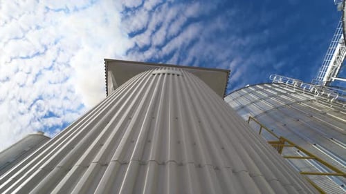 Metal construction on the modern factory. Storage tanks for processing grains on sky background.