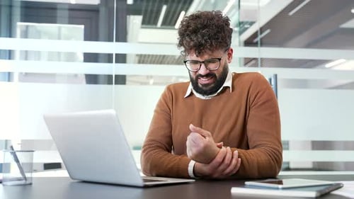Man Suffering Wrist Pain While Working on Laptop