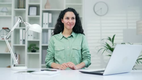Süße junge Mitarbeiterin hebt mit einer Geste den Daumen hoch - es gibt eine tolle Idee, am Computer zu sitzen