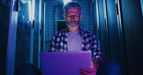 Mann sitzt mit Laptop auf dem Boden