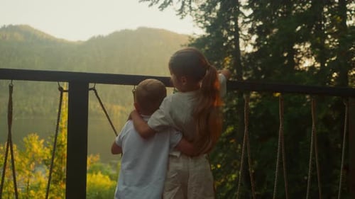 Sister Hugs Brother Watching Lake Surrounded By Forest