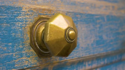 Gold Metal Handle On An Old Wooden Door Painted Blue in slowmotion in france.