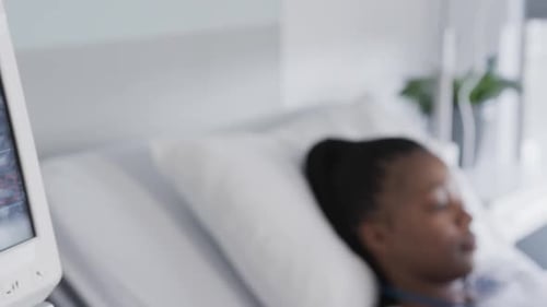 African american female patient using tablet lying in bed in hospital room, slow motion