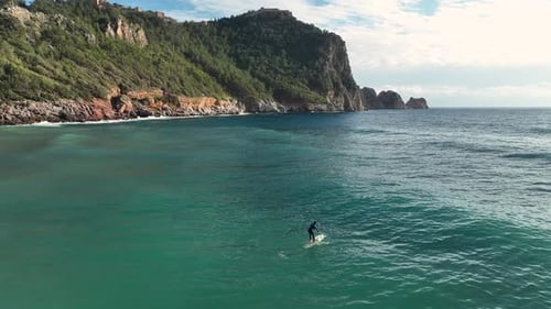 Person Paddleboarding in Beautiful Coastal Waters
