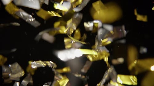 Gold and Silver Confetti Falling on Black Backdrop