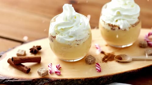 Christmas and Seasonal Drinks Concept - Snow Falling Over Glasses of Eggnog