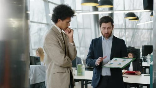 Businessmen Discussing Report in Modern Office
