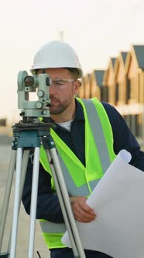 Surveyor Engineer Using Theodolite and Examining Blueprints on Construction Site