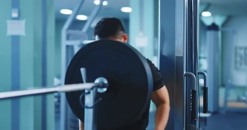 Asiatischer Sportler, Bodybuilder, legt Bandscheiben an und bereitet eine schwere Hantel für das Gewichtheben vor