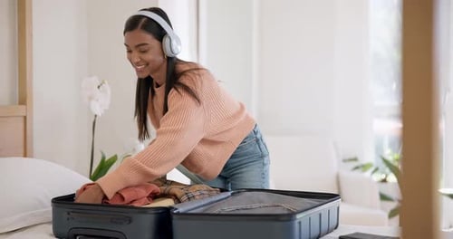 Headphones, happy and woman packing suitcase in home for travel, holiday journey