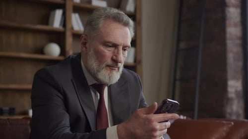Businessman Reading Message on Smartphone and Nodding Head